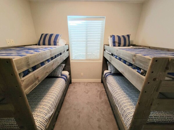 Una habitación con dos literas, una ventana con persianas y suelo cubierto de moqueta.