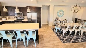 A modern kitchen with dark cabinets, a central island, and hanging pendant lights. - Fully Equipped Vacation Home in Paradise Village (Santa Clara)