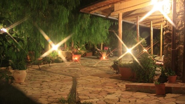 A stone-paved courtyard with potted plants and a wooden pergola structure. - Nature and relaxation (Sicilia)