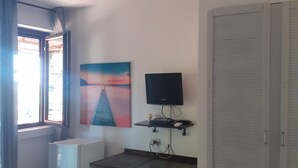 A room with a bed, a desk, a TV, a painting, and a wardrobe. - Nature and relaxation (Sicilia)