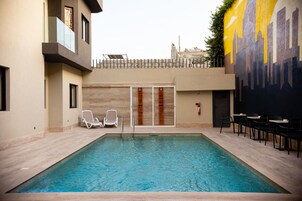 Una piscina con sillas de descanso y un mural en la pared contigua.