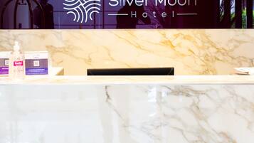 A reception desk at the Silver Moon Hotel with a marble countertop and a logo above it.