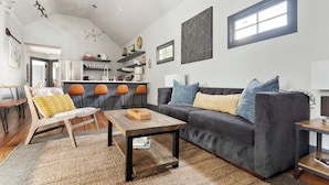 Un salon moderne avec un canapé gris foncé, une table basse en bois et un tapis de couleur claire.