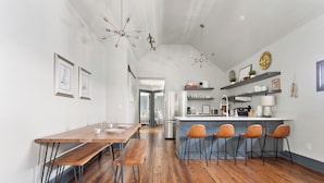 Une cuisine moderne dotée d’un îlot central, de tabourets de bar et d’un coin repas avec une table et des bancs en bois.