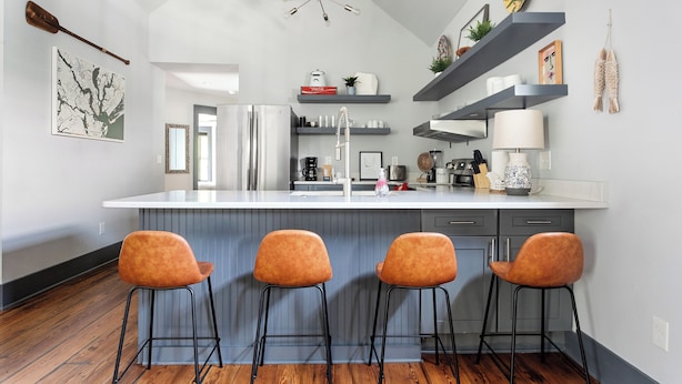 Une cuisine moderne dotée d’un îlot central, de tabourets de bar et de divers appareils électroménagers.