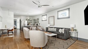 Uma sala de estar moderna com um sofá cinzento, uma mesa de centro e uma área de jantar com mesa e cadeiras.