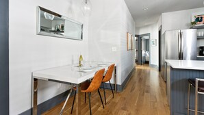Uma cozinha moderna com bancada branca, eletrodomésticos de aço inoxidável e piso de madeira.