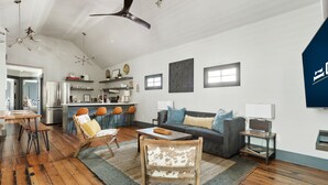 A modern living room with a sofa, chairs, a coffee table, and a kitchen in the background. - Only 2 Blocks to King | The Gemstone (Suite B) (Charleston)