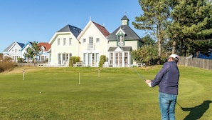 Golfkenttä, jossa on klubitalo ja taustalla näkyy taloja.