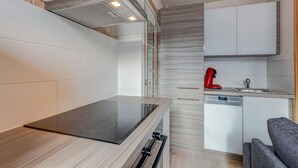 Une cuisine moderne avec un pare-feu en verre, des armoires blanches et un lave-vaisselle encastré.