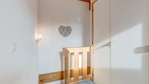 Une pièce avec un berceau en bois, un mur blanc orné d’un décor en forme de cœur et une porte.