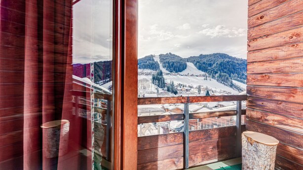 Une cabane en bois dotée d’un balcon donnant sur un paysage montagneux enneigé.