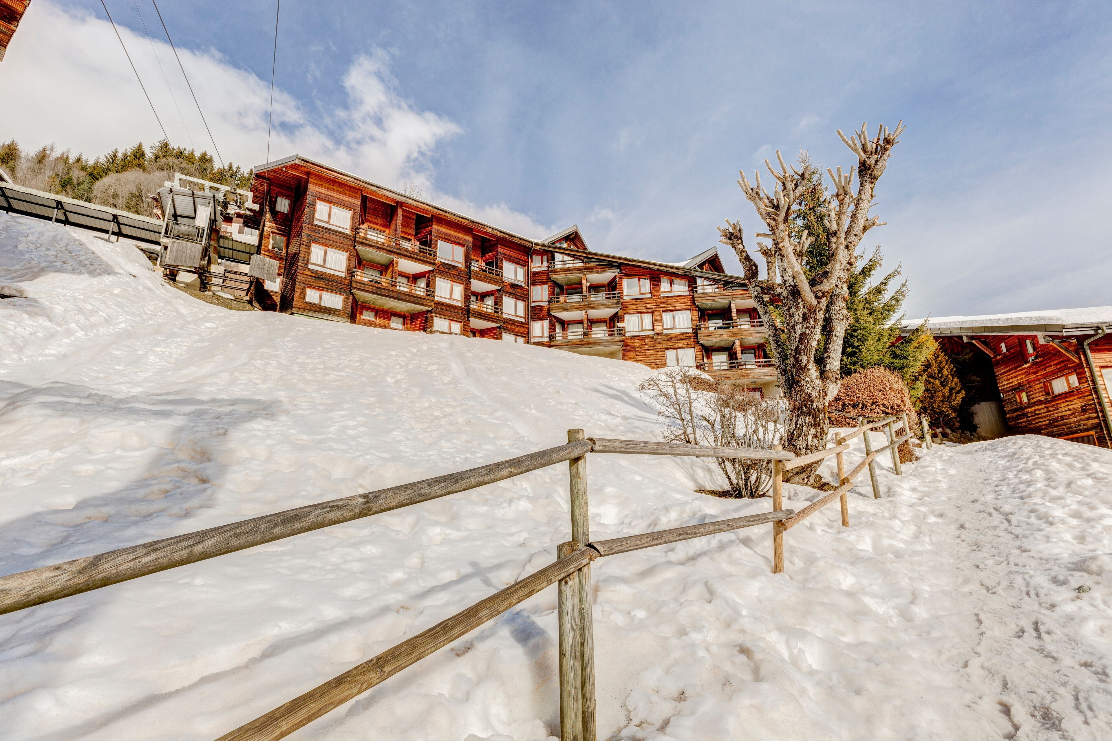 A wooden chalet-style building with multiple balconies, surrounded by snow.