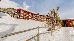 Un bâtiment de style chalet en bois, doté de nombreux balcons et entouré de neige.