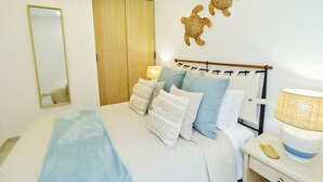 A bedroom with a bed, bedside lamps, a nightstand, and a wall-mounted mirror.