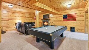 A pool table in a room with wooden walls and a stone fireplace. - Freedom Lodge | Sleeps 12 | 4BR + Loft | Hot Tub, Pool Table & Covered Decks (Rockbridge)