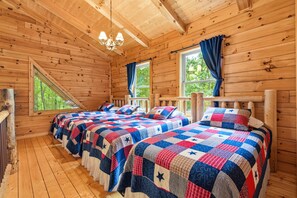 A cabin with two beds, a chandelier, and windows with curtains. - Freedom Lodge | Sleeps 12 | 4BR + Loft | Hot Tub, Pool Table & Covered Decks (Rockbridge)