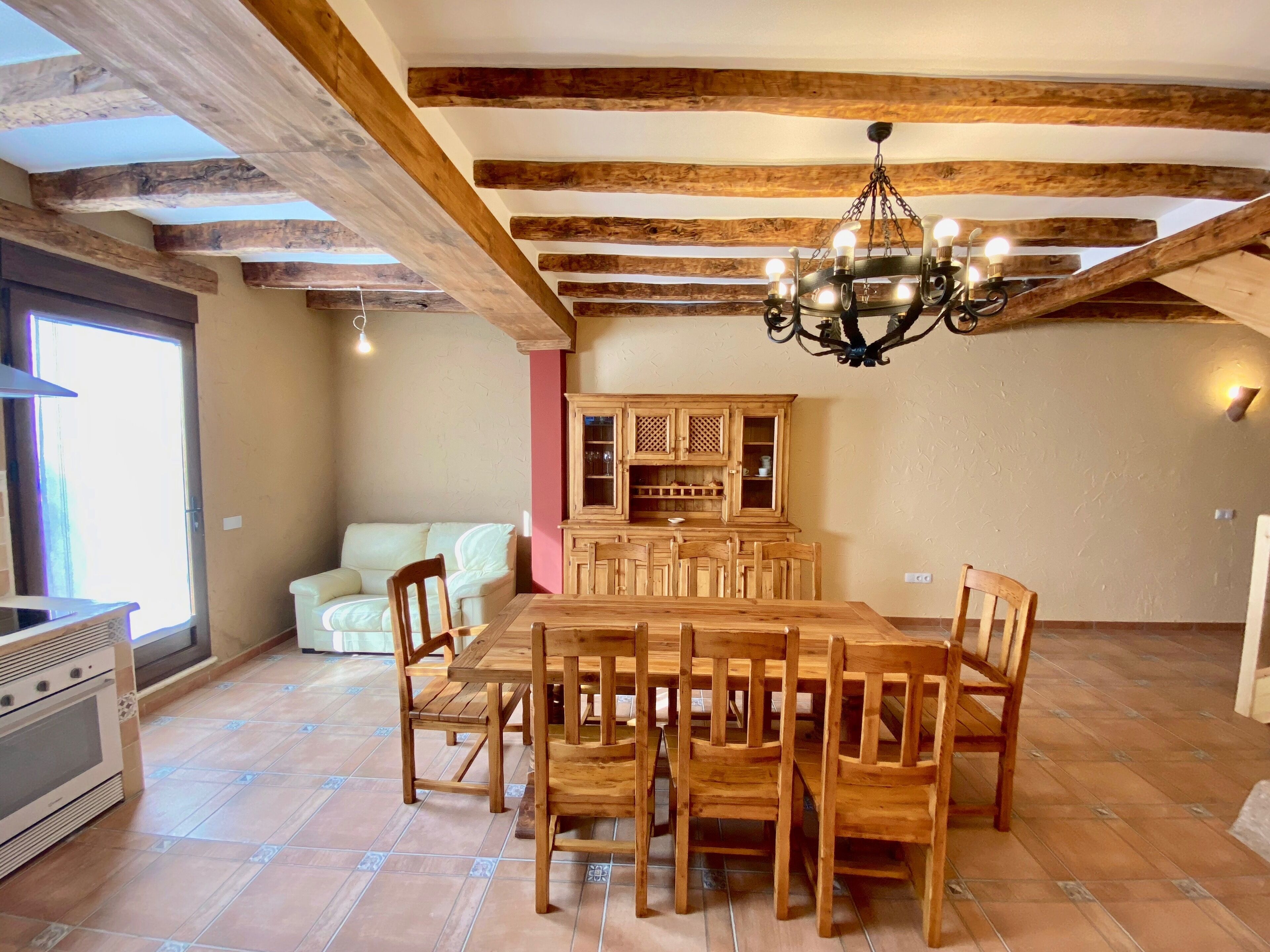 A dining area with a wooden table and chairs, a chandelier, and a cabinet with glass doors.