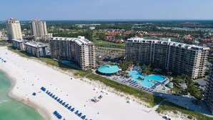 Un resort con varios edificios altos, una playa y una piscina central.