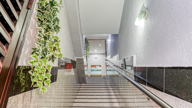 A staircase with handrails, a plant on the left, and a sign at the top. - Hotel Urban Mooca (São Paulo)