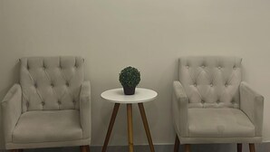 A room with two beige armchairs, a small round table with a potted plant, and a modern wall art piece. - Hotel Urban Mooca (São Paulo)