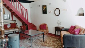 A living room with a glass-top coffee table, a sofa, a patterned rug, a red staircase, and a wall with decorative items. - A warm, 100% eco-responsible hotel to recharge your batteries (Morsains)