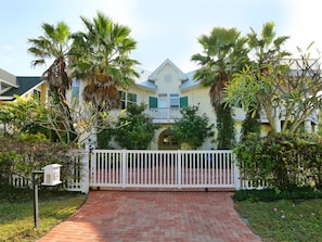 A two-story house with a brick pathway leading to a white gate. - Sunset Shores: Stunning sunset views over the beach! (Anna Maria)