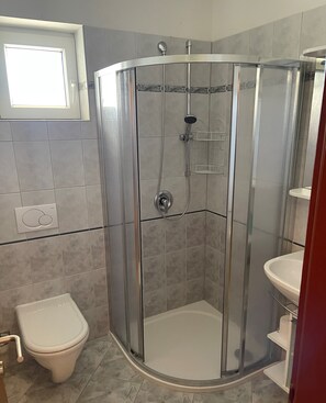 A shower enclosure with a glass door, a white toilet, and a sink with a mirror. - Beautiful 3-bed Apartment With big Terasse in Nin (Nin)