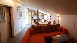 Una sala de estar moderna con un sofá modular, una mesa de comedor y una cocina al fondo.