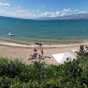 A beach with people sunbathing and swimming, a boat on the water, and mountains in the background. - Beautiful 3-bed Apartment With big Terasse in Nin (Nin)