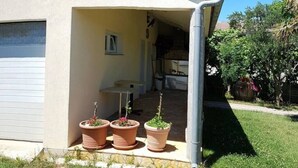 Una casa de un piso con un porche cubierto, un garaje y tres macetas.