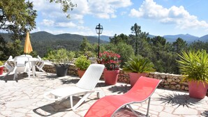A patio with lounge chairs, potted plants, and a stone floor. - LA RESTONICA (Fréjus)