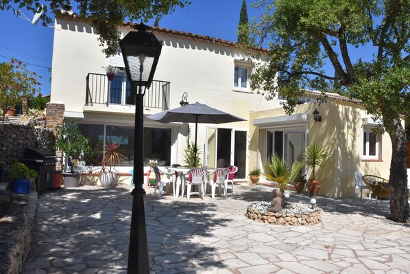 A courtyard with stone flooring, outdoor furniture, and potted plants.