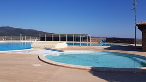 A swimming pool with a view of mountains, a covered seating area, and a stone building. - LA RESTONICA (Fréjus)