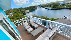 A deck with outdoor seating, a view of a lake, and a boat dock in the background.