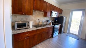 A kitchen with wooden cabinets, a microwave, a toaster, a sink, and a refrigerator.