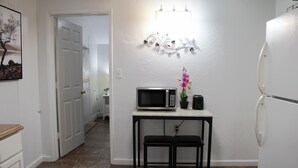 A kitchen with a white refrigerator, a microwave on a small table, two black stools, and a decorative wall piece above the microwave. - National parks and nice place to relax (Tulare)