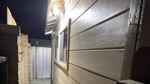 A narrow concrete pathway flanked by wooden fences and a building with a window. - National parks and nice place to relax (Tulare)