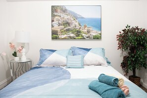 A bedroom with a bed, pillows, a nightstand with a lamp, a framed picture on the wall, and a potted plant. - National parks and nice place to relax (Tulare)