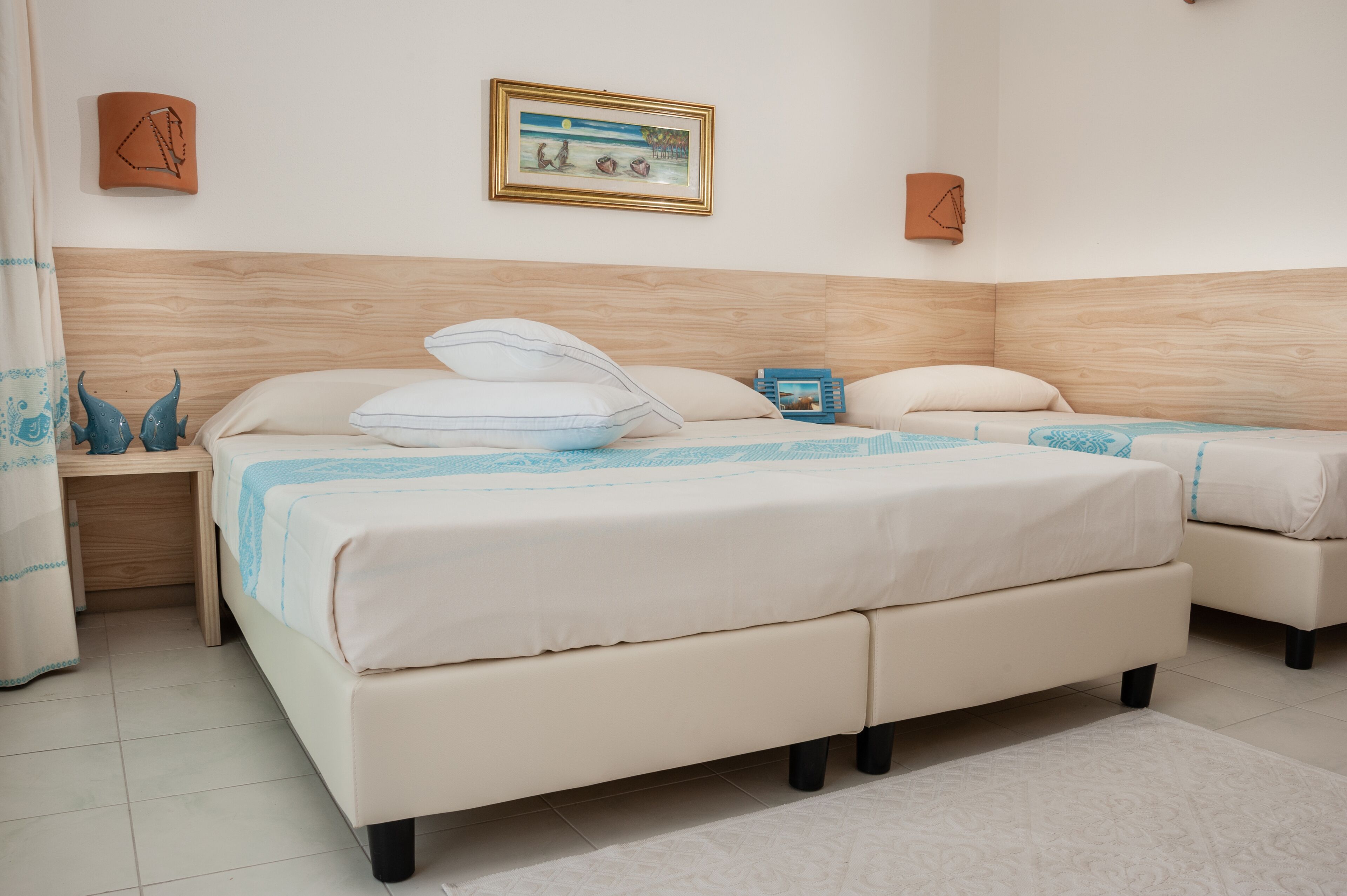 Una camera da letto con un letto grande, un letto più piccolo, un comodino e una mensola a parete.