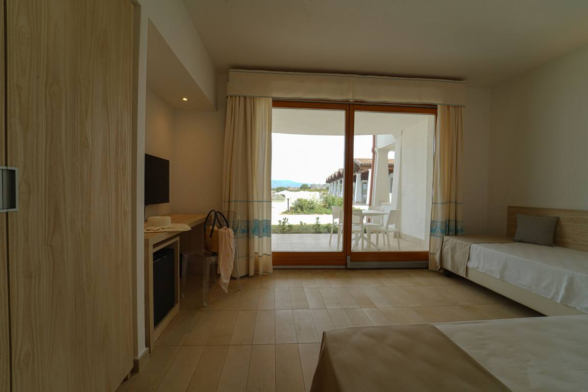 A hotel room with a bed, a desk with a chair, a television, and a view of the outdoors.