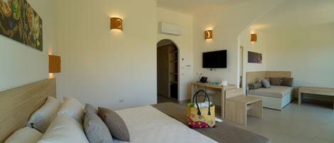 A hotel room with a bed, a desk, a sofa, and a TV.