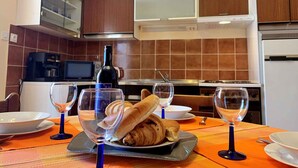 A dining area with a table set for two, featuring a bottle of wine, two wine glasses, a croissant, and a plate of food. - Holiday apartment with sea view and air conditioning (Čižići)