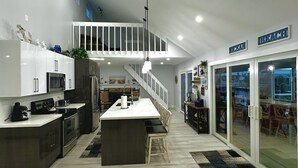 A modern kitchen with a central island, a dining area with a view, and a staircase leading to an upper level. - Breath taking canal, pool home with golf access. 15 minutes from beaches. (Port Charlotte)