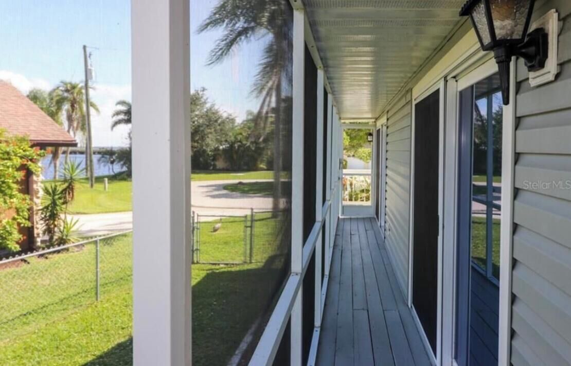 A covered porch with a view of a grassy yard and a house in the background.