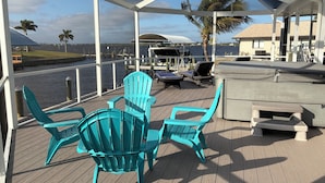 A covered deck with turquoise chairs, a small table, and a bench. - Breath taking canal, pool home with golf access. 15 minutes from beaches. (Port Charlotte)