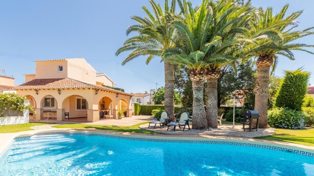A poolside area with a pool, palm trees, and a building with arches. - 5 minutes from the beach! Ideal house for families, with private pool. (La Xara)