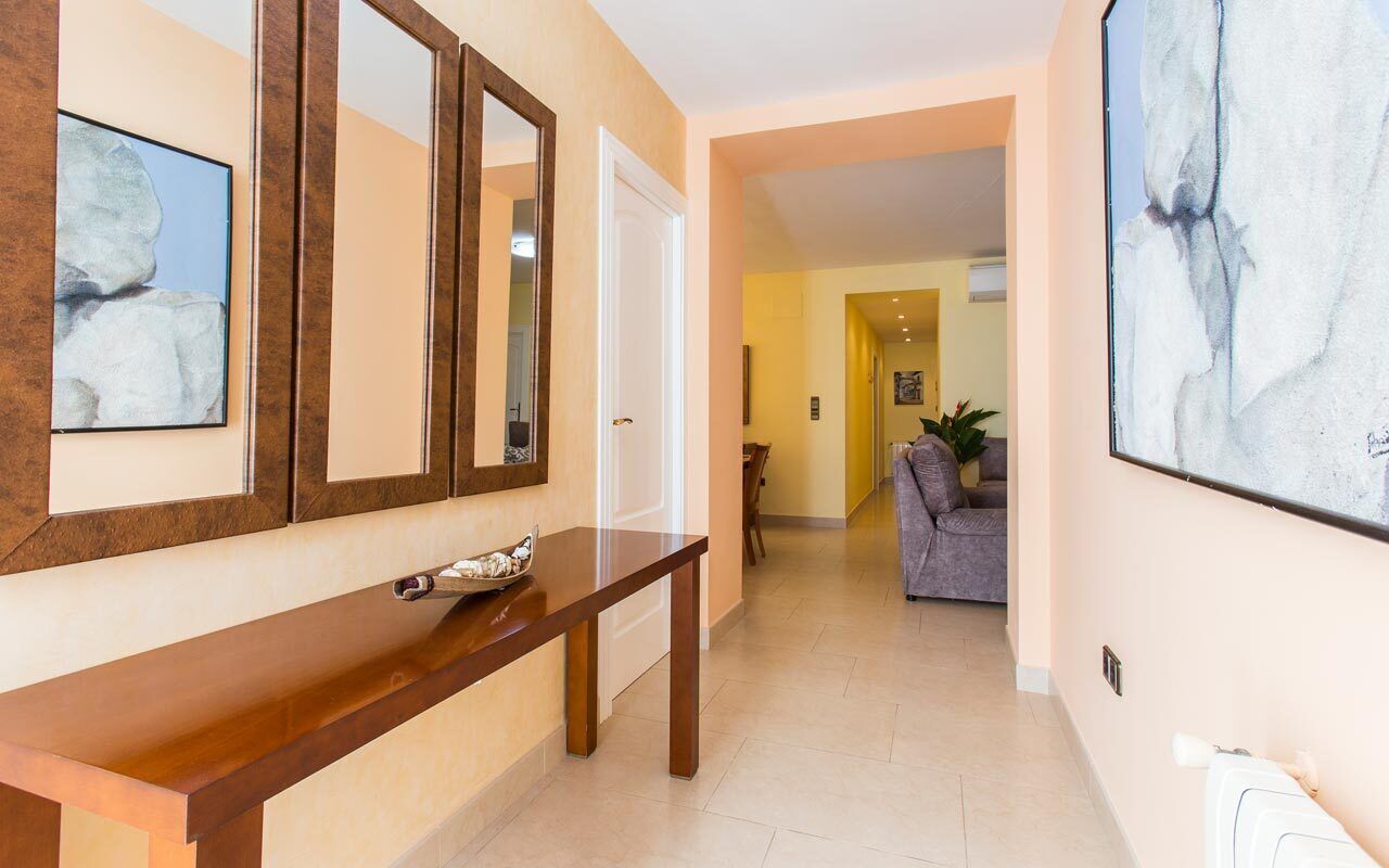 Un couloir avec un banc en bois, une porte blanche et un tableau abstrait encadré accroché au mur.
