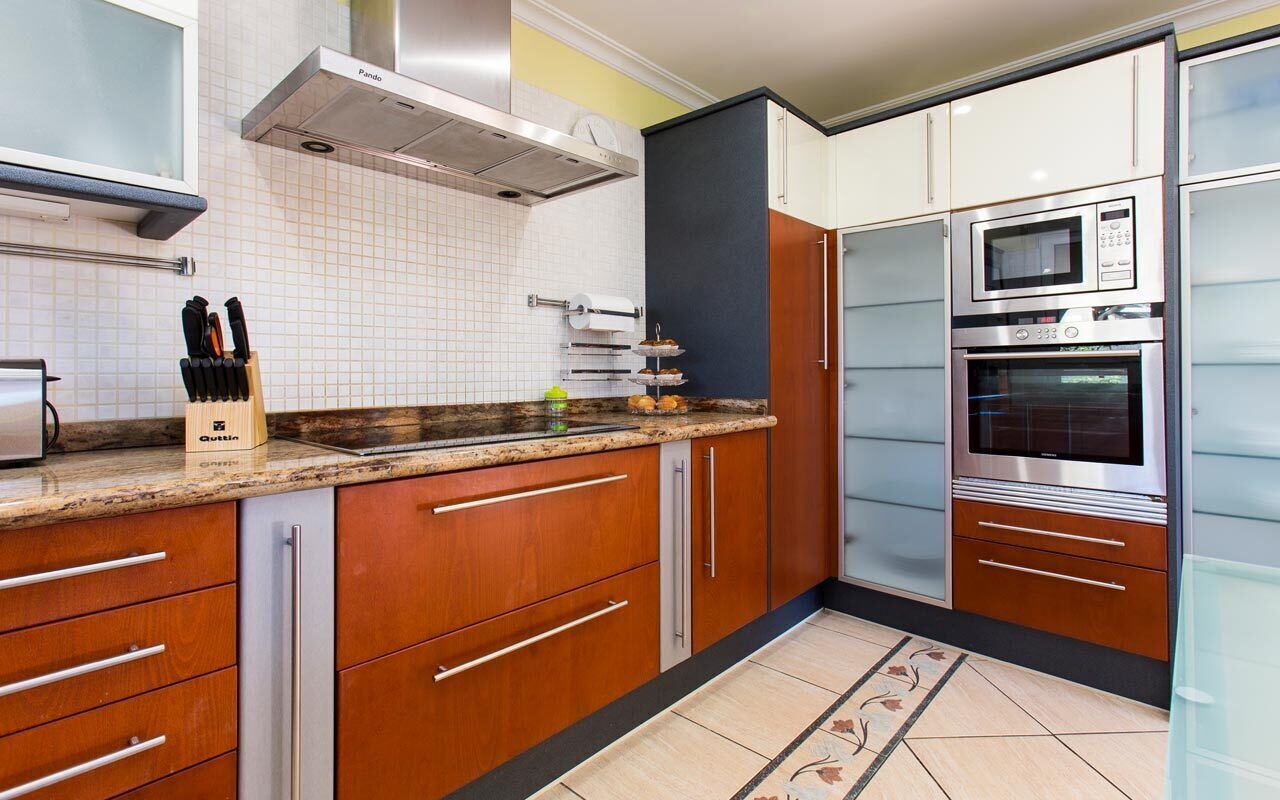 A modern kitchen with wooden cabinets, stainless steel appliances, and a tiled backsplash.