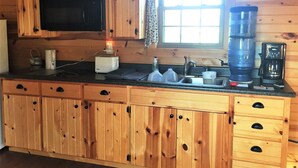 Une cuisine en bois équipée d’un four à micro-ondes encastré, d’une machine à café et d’un évier.